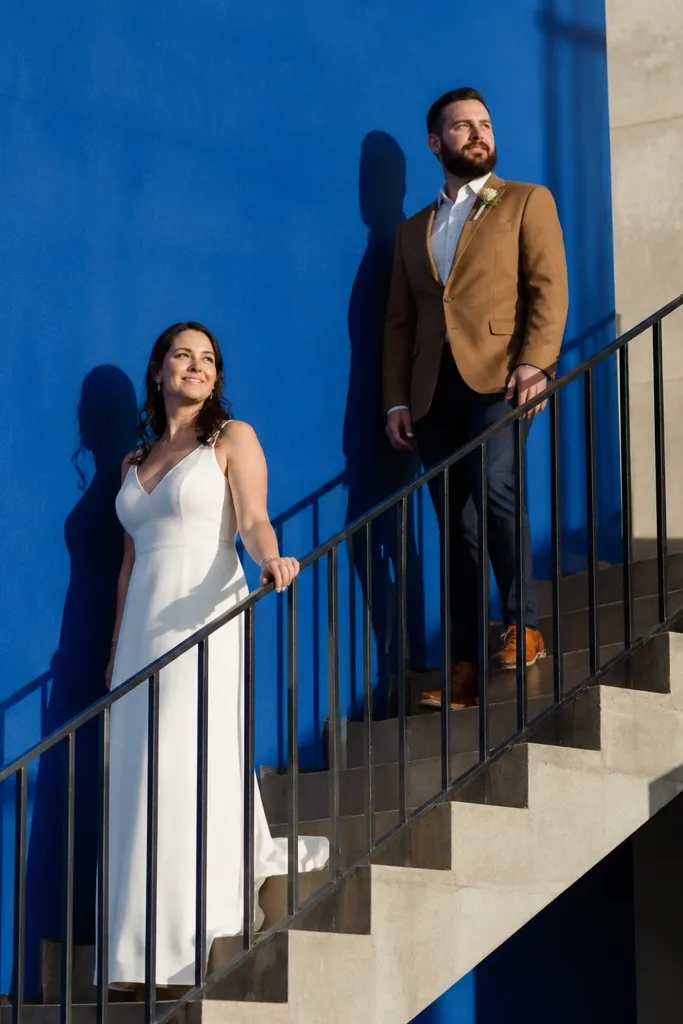 Couple posing on stairs in front of a bright color wall