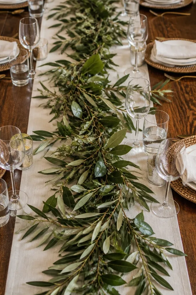 Green leaf cuttings scattered on an off-white linen runner