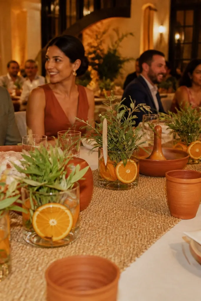 Oat table runner with terracotta accents and short vases of citrus branches