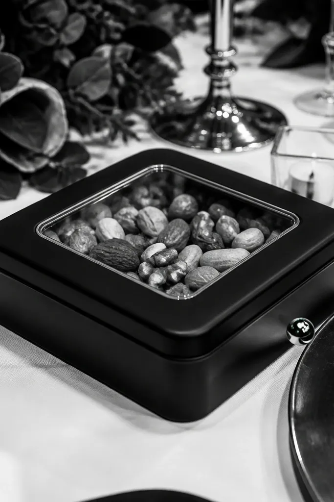 Matte-black tin with a clear window label showing almonds and pistachios inside