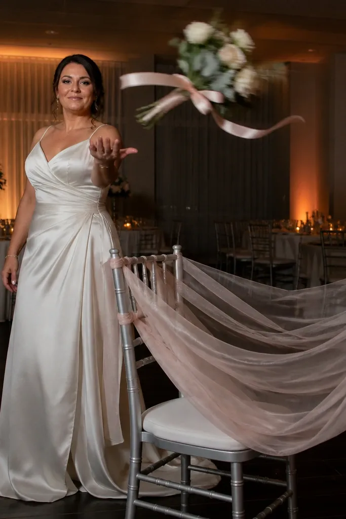 Bouquet wrapped with ribbons suspended above a soft net or drape