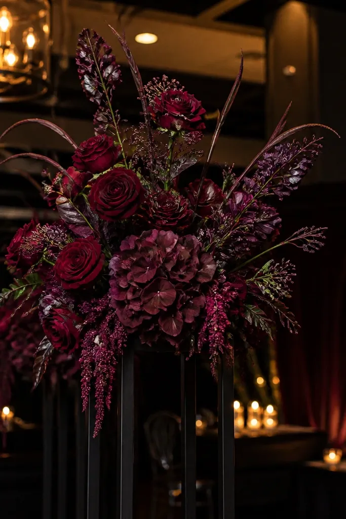 Burgundy faux florals on black metal stands for a ceremony backdrop