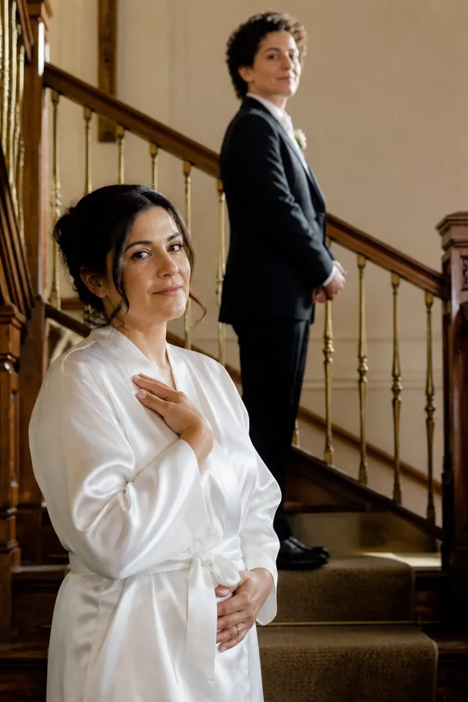 Couple on a staircase landing, one hand near the chest, looking at each other
