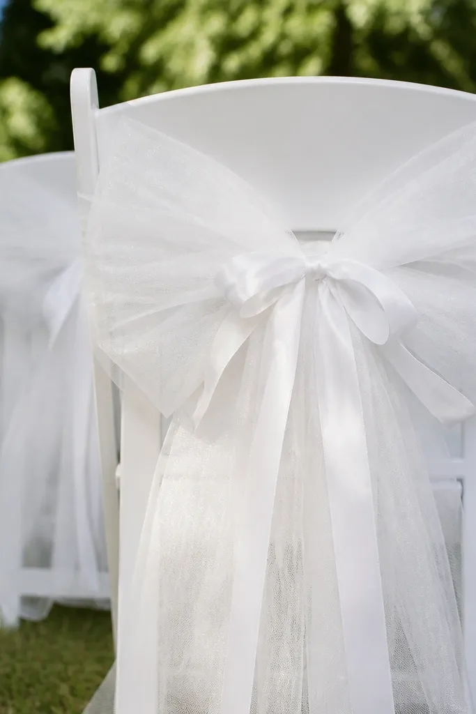 White tulle ribbon bow tied to the back of a chair with a satin tie
