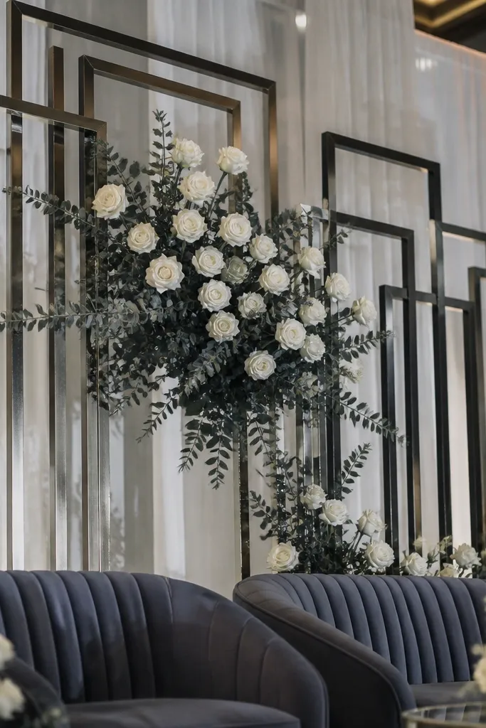 White geometric frame filled with roses and eucalyptus on a wedding stage